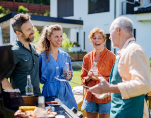 Family members talking and laughing by the grill at a cookout.