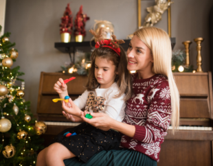 Mother and child sitting next to a Christmas Tree